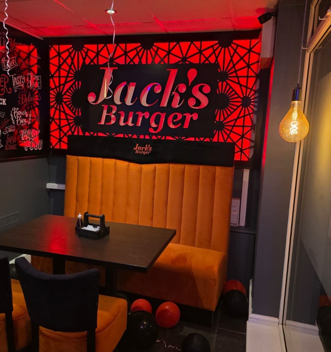 Booth seating beneath the illuminated Jack's Burger sign inside a branch